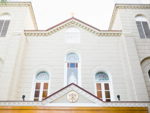 A bright, white classical building facade with arched windows and a decorative emblem.