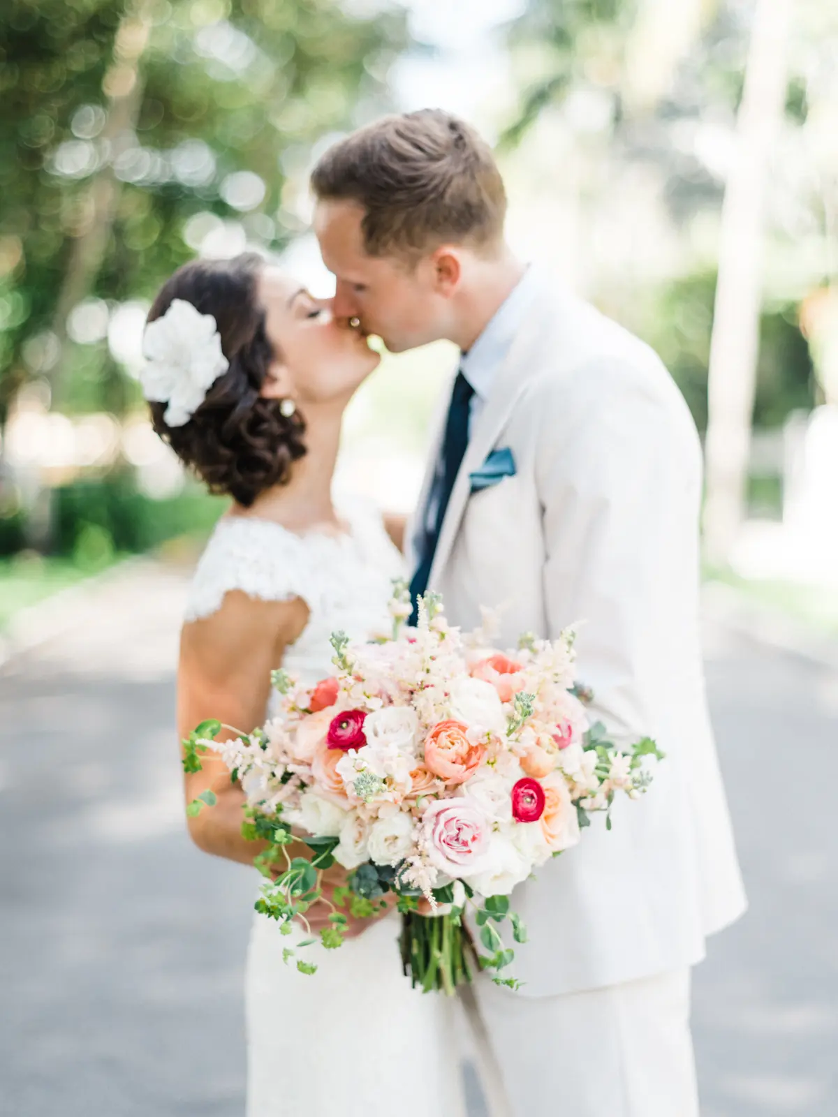 Bride and groom sharing a kiss with a beautiful bouquet.